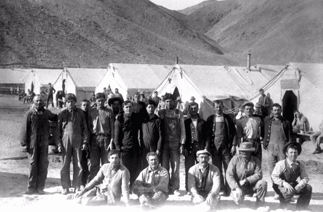 (ca. 1912)^*โ Group photo of workers posing in front of their living quarters before the start of a long workday.